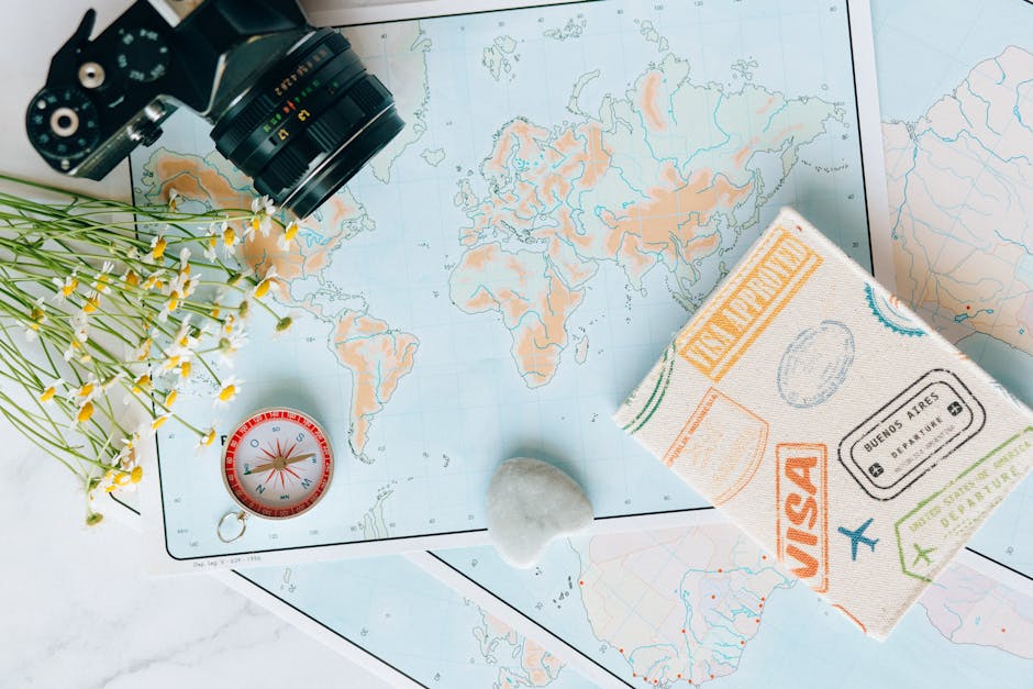 Flat lay of travel essentials: maps, camera, compass, and travel journal for planning adventures